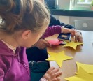 Foto_ Seitenprofil einer Schülerin beim Basteln eines gelben Papiersterns