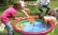 Das Foto zeigt ein Kind mit den Händen in einem Schwimmbassin sowie ein Mädchen mit einem Köcher mit Plastikenten..  