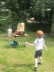 Das Foto zeigt 2 Kinder an einer Wurfmaschine und einen kleinen orangen Teddybär, der durch die Luft fliegt. 